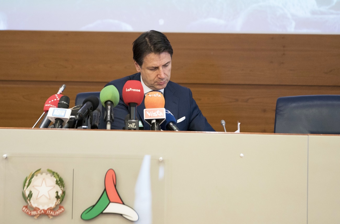 Il presidente del Consiglio Conte seduto durante una conferenza stampa